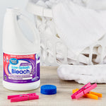 Great Value Low-Splash Bleach bottle displayed on a laundry room surface with towels, clothespins and a laundry basket in the background