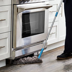 Great Value microfiber duster being used to clean under a stainless steel oven on wood floor