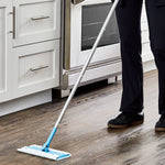 Lifestyle shot of a person mopping a kitchen floor with the blue Great Value wet and dry mop near stove cabinets
