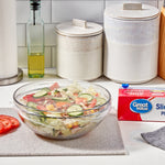 Kitchen scene with salad bowl covered in plastic wrap and Great Value box at right