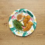 Great Value seasonal patterned paper plate on a wooden table topped with mashed potatoes, gravy, green beans and fried chicken strips