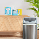 Two Great Value trash bag boxes displayed on a wooden surface next to a stainless steel trash can in a styled room scene
