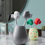 Bathroom scene with four toothbrushes topped with Grin brushcap covers displayed in two cups on a marble counter