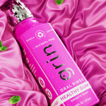 Magenta Grin oral rinse bottle lying on a magenta satin fabric with mint leaves.