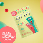 Tilted Grin Kiddo packaging floating on a yellow background with colorful spheres and a callout reading “clean tongue. healthy tongue.”