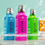 Magenta Grin oral rinse bottle centered among blue and green variant bottles on a wet surface.