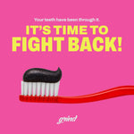 Close-up of a red toothbrush with a dollop of black Grind charcoal toothpaste against a pink background and bold text