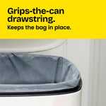 Close view of a gray Glad ForceFlex bag fitted inside a trash can with a yellow header reading ‘Grips-the-can drawstring. Keeps the bag in place.’