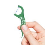 Hand holding a green GUM Twisted Mint floss pick against a white background, showing grip and twisted floss
