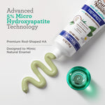 Tube of Guru Nanda toothpaste squeezed to show pale green paste next to its teal cap and text about hydroxyapatite technology.