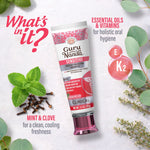 Flatlay style image of a GuruNanda Sensitive toothpaste tube with mint leaves, cloves and callouts for essential oils and vitamins.
