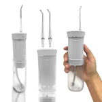 White GuruNanda travel water flosser displayed assembled, with two spare tips and a hand holding the device to show scale