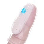 Close-up of a clear silicone finger toothbrush on a fingertip with a dab of blue paste