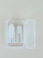 Two clear silicone finger brushes stored inside a translucent plastic case on a pale surface