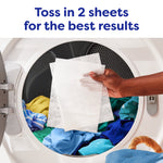 Hand placing two white dryer sheets into a dryer full of colorful clothes with instruction text 'Toss in 2 sheets for the best results'.