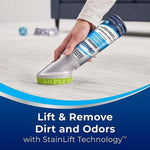 Hand applying Woolite carpet & upholstery foam cleaner with green bristle brush to a light-colored carpet, lift and remove dirt text