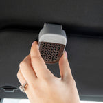 Hand attaching a Yankee Candle Sidekick visor clip to a car visor, showing branded top and grille