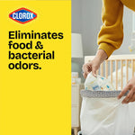 Hand placing a diaper into a lined 4-gallon trash bin beside bold yellow panel reading 'Eliminates food & bacterial odors'