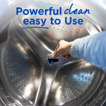Hand placing a blue Purex laundry pac into the interior of a stainless steel washing machine drum
