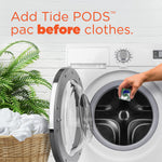 Hand dropping a Tide POD into an open front-load washing machine next to a laundry basket and plant, with text advising to add pod before clothes.