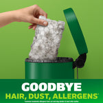 Hand holding a used Swiffer Hair Magnet cloth full of hair being emptied into a small trash can against a green background