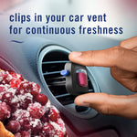 Hand placing a Febreze Car cranberry crumble vent clip into a circular car vent with sugared cranberries in foreground