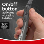 Hand gripping a charcoal Colgate toothbrush showing the on/off button and textured handle for vibration control