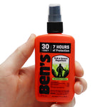Hand holding a small orange Ben's pump spray bottle with label showing 30% DEET and 7 hours of protection