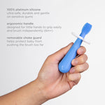 Hand holding a blue silicone baby toothbrush with removable choke guard and on-image product feature text