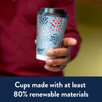 Hand holding a Chinet Comfort patriotic patterned paper cup with black lid against blurred background