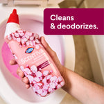 Hand holding a pink Clorox Scentiva toilet cleaning gel bottle above a toilet, callout text reads “Cleans & deodorizes.”