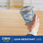 Hand holding a Dixie patterned cup with gray leak-resistant lid showcased over a wooden table