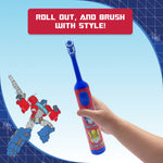 Hand holding a red and blue Equate Transformers kids electric toothbrush with Optimus artwork and a Transformers illustration in background