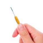 Hand holding a GUM Proxabrush interdental brush by its orange grip showing small conical bristle head
