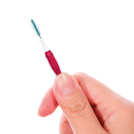 Hand holding a small pink-handled GUM proxabrush interdental brush against a white background