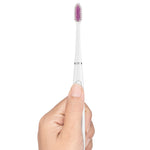 Hand holding the white G•U•M Sonic Power toothbrush vertically, showing bristles, slim handle and power button.