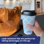 Hand holding a Hefty gray lattice-pattern disposable hot cup with black lid in a kitchen setting with bag nearby