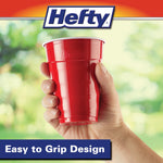 Hand holding a red Hefty party cup against a soft green background with Hefty logo above