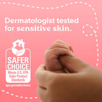 Close-up of adult hand holding infant hand with text about dermatologist testing and EPA Safer Choice logo on pink background