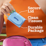 Hand holding a blue Kleenex Snap & Go on-the-go tissue case with callouts for secure lid, clean tissues and durable package