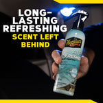 Hand holding a Meguiar's Air Re-Fresher trigger bottle with overlay text 'Long-Lasting Refreshing Scent Left Behind'.