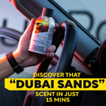 Hand holding a Meguiar's Dubai Sands Air Re-Fresher can near a steering wheel with promotional text overlay