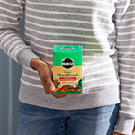 Person holding a boxed Miracle-Gro tomato plant food in front of their torso, showing product branding and label