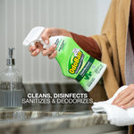 Hand holding an OdoBan green disinfectant spray bottle over a bathroom sink with cleaning text overlay