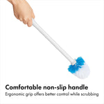 Hand holding the white toilet brush by its ergonomic non-slip handle, brush head visible.