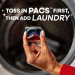 Hand holding a red-and-blue laundry pac in front of a washing machine with usage instruction text