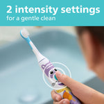 Hand holding a Philips Sonicare kids toothbrush showing the power button and pet design