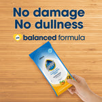 Hand holding a pouch of Pledge multisurface wipes over a wood surface with text 'No damage No dullness'.