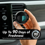 Hand holding a black-and-teal Refresh Your Car mini diffuser in front of a vehicle air vent with freshness claim banner.
