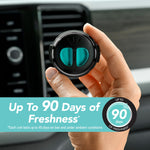 Hand holding a black circular Refresh Your Car mini vent diffuser showing teal refill in front of car vent